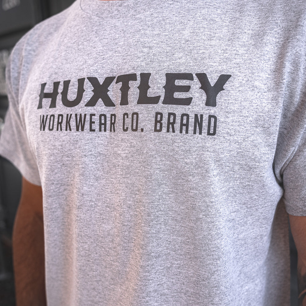 
                  
                    Detailed view of the Huxtley Workwear logo printed across the chest on a heather grey t-shirt. Built tough for everyday wear on site.
                  
                