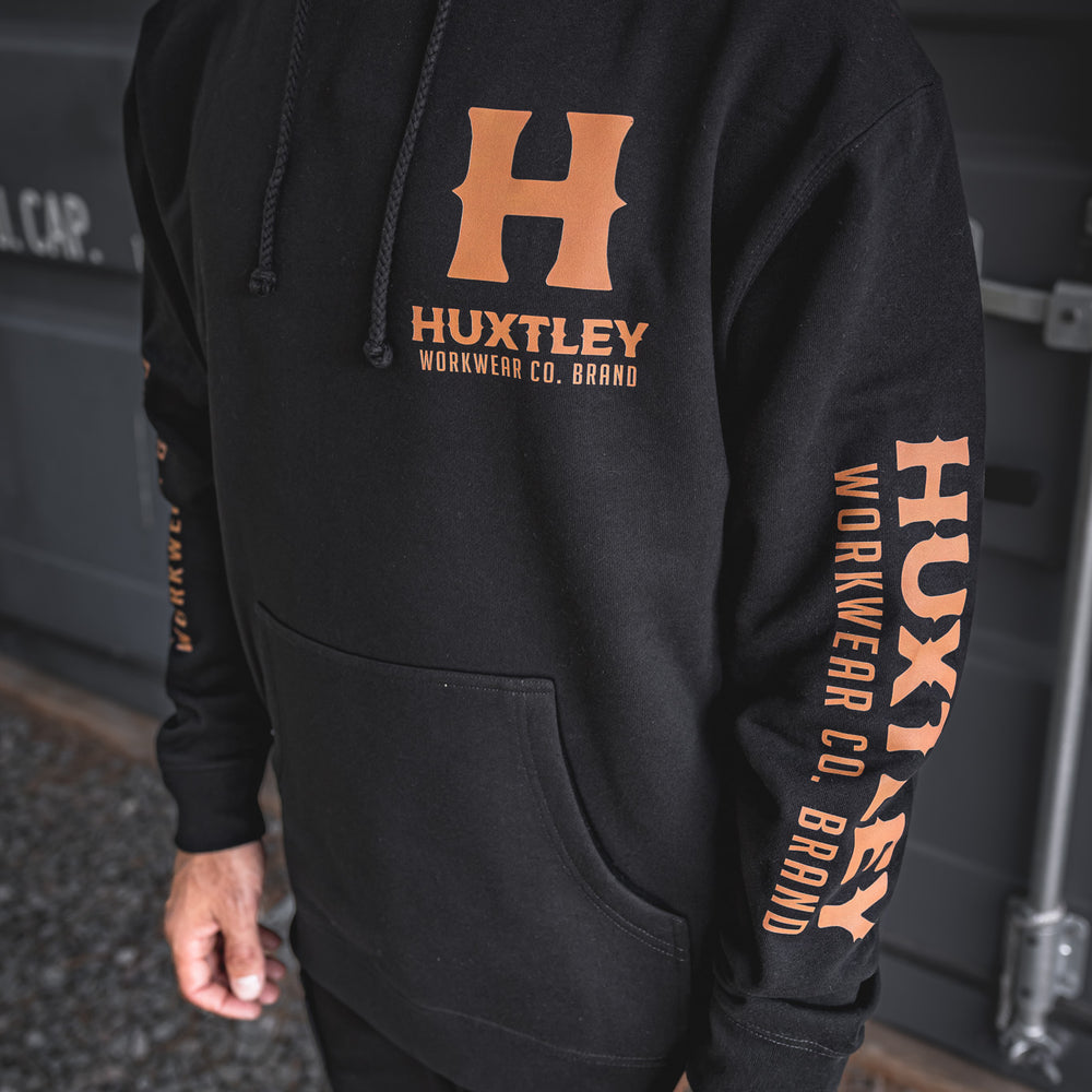 
                  
                    Detailed shot of the Full Print Hoodie’s front and sleeve, featuring bold orange Huxtley Workwear Co. Brand prints on black cotton. Built tough for the jobsite, styled for the street.
                  
                