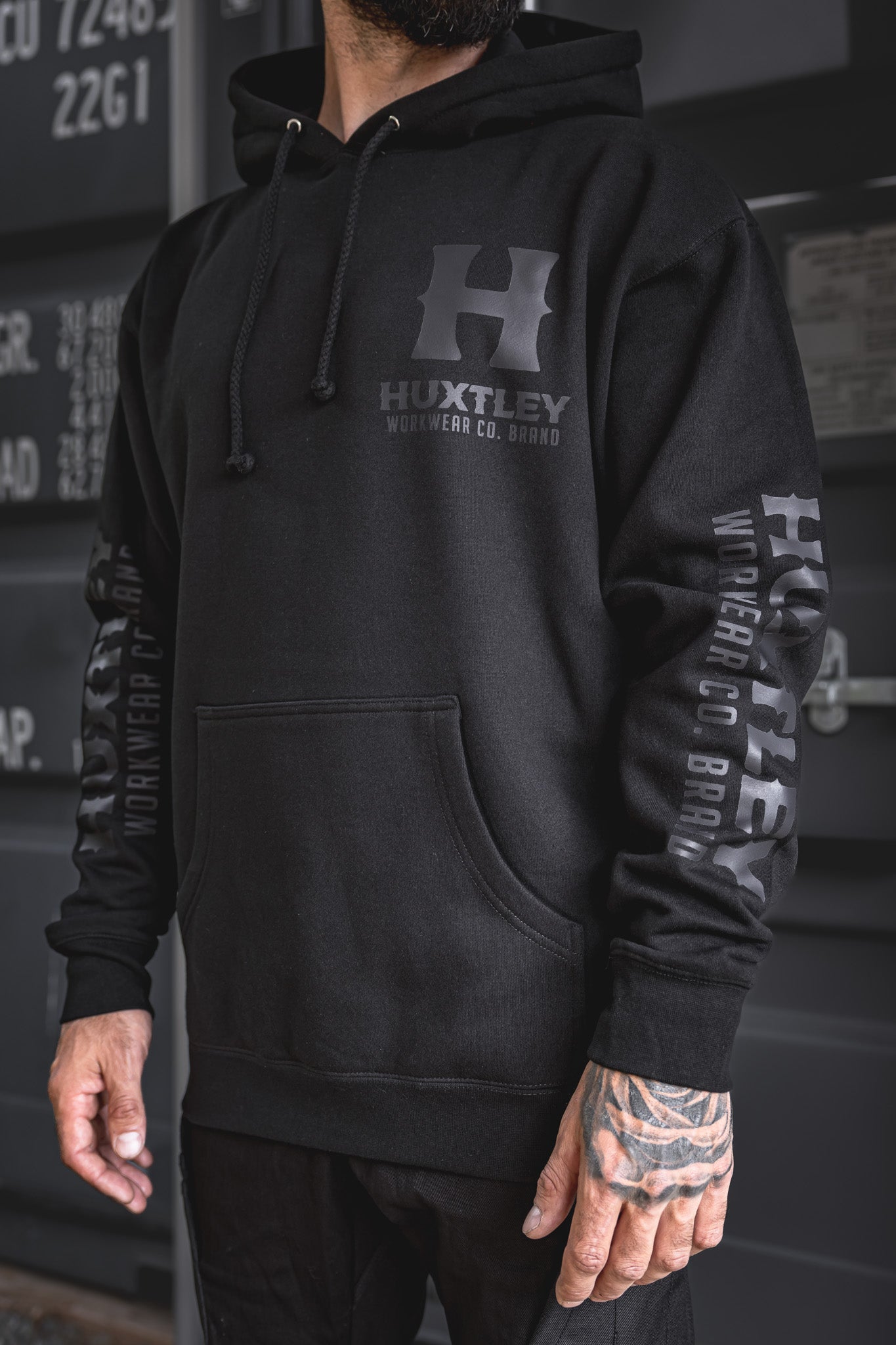 
                  
                    Front view of the Huxtley Full Print Hoodie with sleek black-on-black logo print. Minimalist design, heavyweight feel, and clean tonal branding down the sleeves.
                  
                