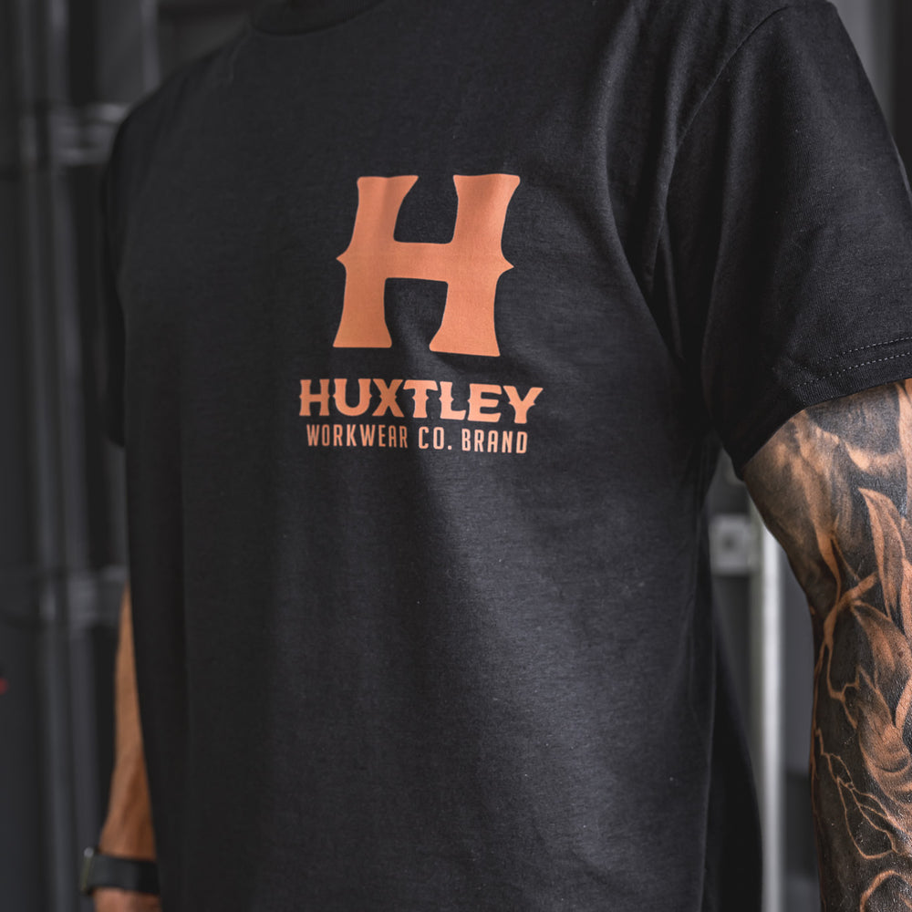 
                  
                    Close-up of the whiskey-colored Huxtley logo on the chest of the Full Print tee. Clean lines, bold print, and premium black cotton.
                  
                