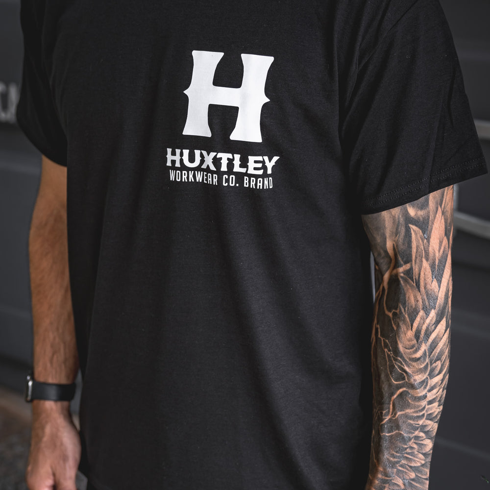 
                  
                    Close-up of the Huxtley Full Print tee featuring the bold white logo on the chest. Built tough with standout contrast.
                  
                