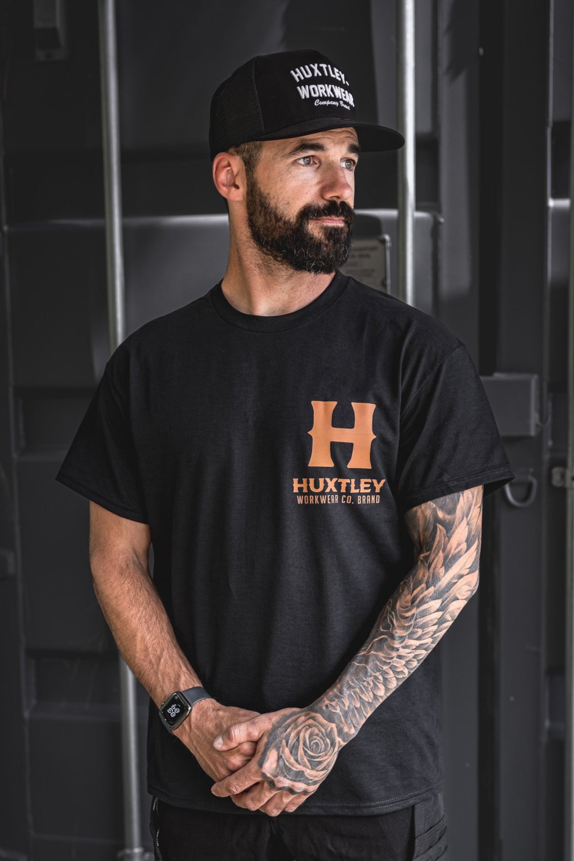 
                  
                    Front view of the Huxtley Full Print t-shirt featuring the whiskey-colored logo on black. Classic workwear fit with bold branding.
                  
                