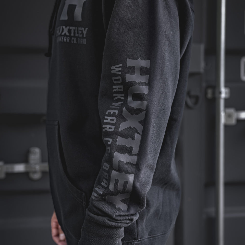 
                  
                    Detailed side view of the Huxtley Full Print Hoodie featuring tonal black-on-black logo on sleeve and chest. A clean, low-key look with industrial edge.
                  
                