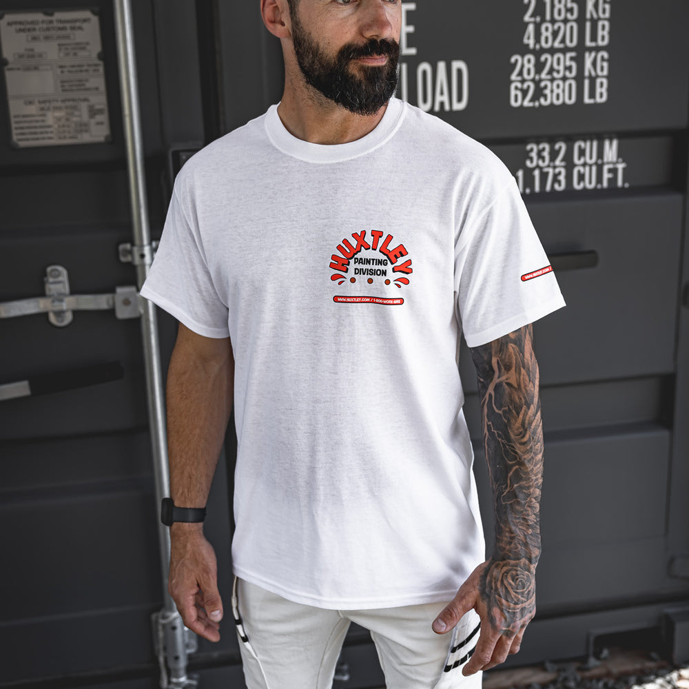 
                  
                    Full-body shot of the Huxtley Painting Division tee styled with white painter pants and a classic Huxtley Throwback snapback. The front chest print pops against the clean white tee, made for pros who keep it tight and roll it right.
                  
                