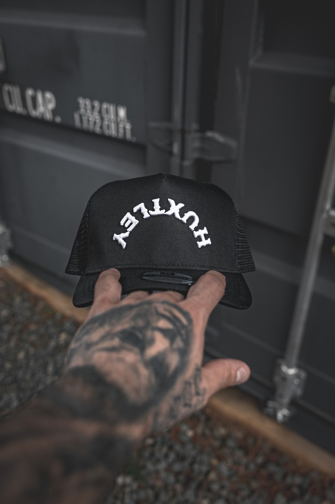 
                  
                    Close-up of the Huxtley Reverse Logo cap in hand. Bold white arched embroidery, structured front, and breathable mesh — made for the grind, built for everyday wear.
                  
                