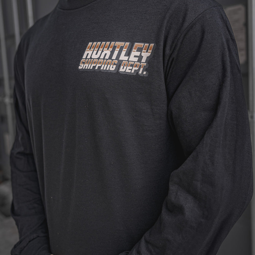 
                  
                    Close-up of the Huxtley Shipping Dept. long sleeve tee in black, showcasing the retro-styled chest logo print in copper gradient. Built for the yard, sharp enough for post-shift beers.
                  
                