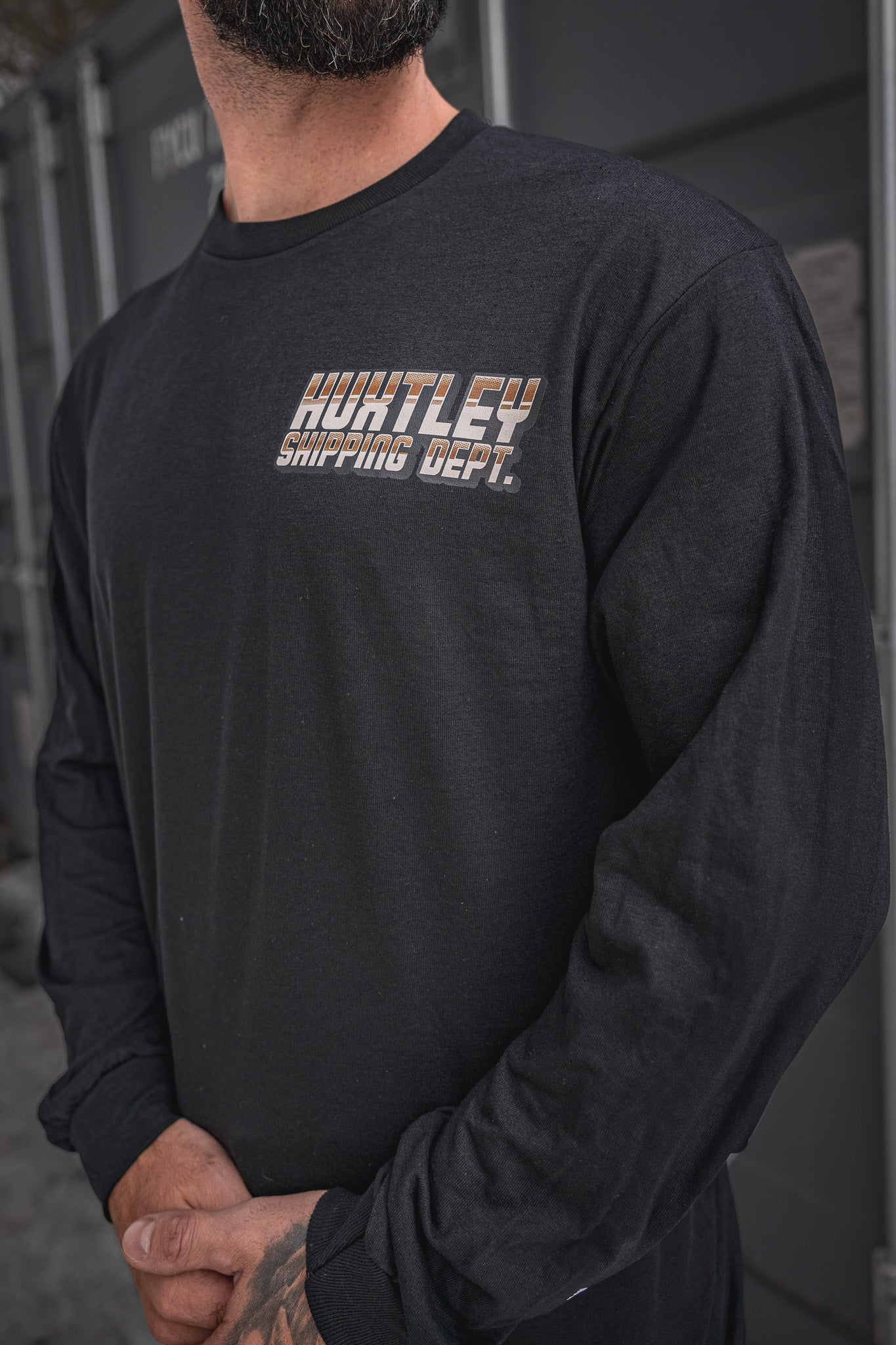 
                  
                    Close-up of the Huxtley Shipping Dept. long sleeve tee in black, showcasing the retro-styled chest logo print in copper gradient. Built for the yard, sharp enough for post-shift beers.
                  
                