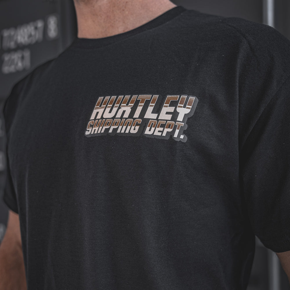 
                  
                    Detailed close-up of the Huxtley Shipping Dept. logo on the chest of the black short sleeve tee. Built for the yard, styled for the street — clean look with vintage truck-shop energy.
                  
                