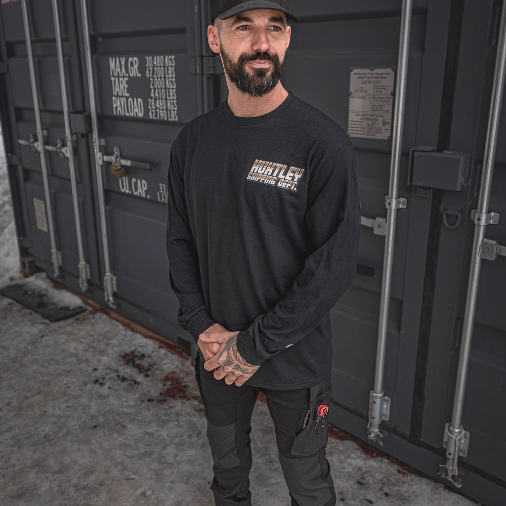 
                  
                    Model wearing the Huxtley Shipping Dept. long sleeve tee in black paired with Huxtley FX-1 Slim Pro Pants Blackout. Rugged workwear with a clean silhouette—made for hard shifts and cold yards.
                  
                