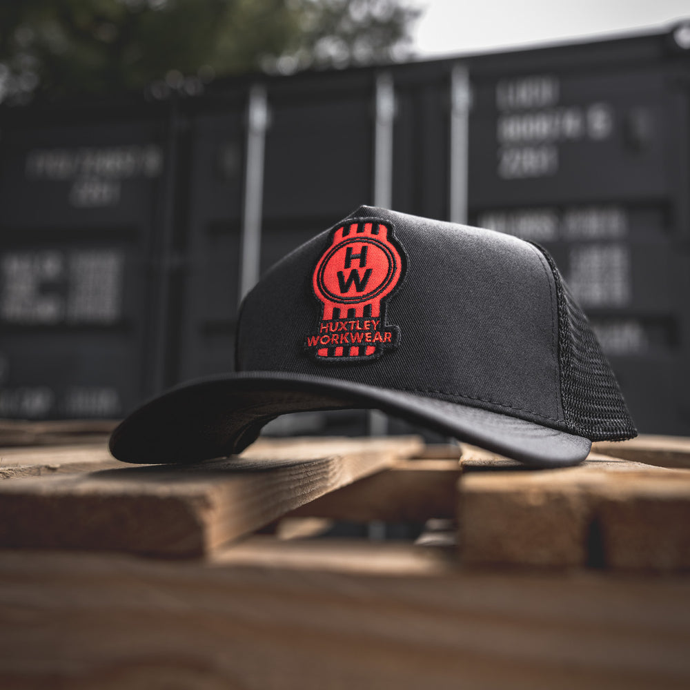 
                  
                    Front and center: the red HW badge on our classic black trucker hat. Tough mesh, curved brim, and built for the jobsite or the weekend run.
                  
                