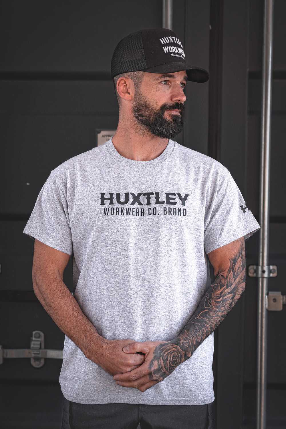 Heather grey t-shirt with bold “HUXTLEY WORKWEAR CO. BRAND” print across the chest and logo hit on the sleeve. Built tough, looks sharp, made for the grind.