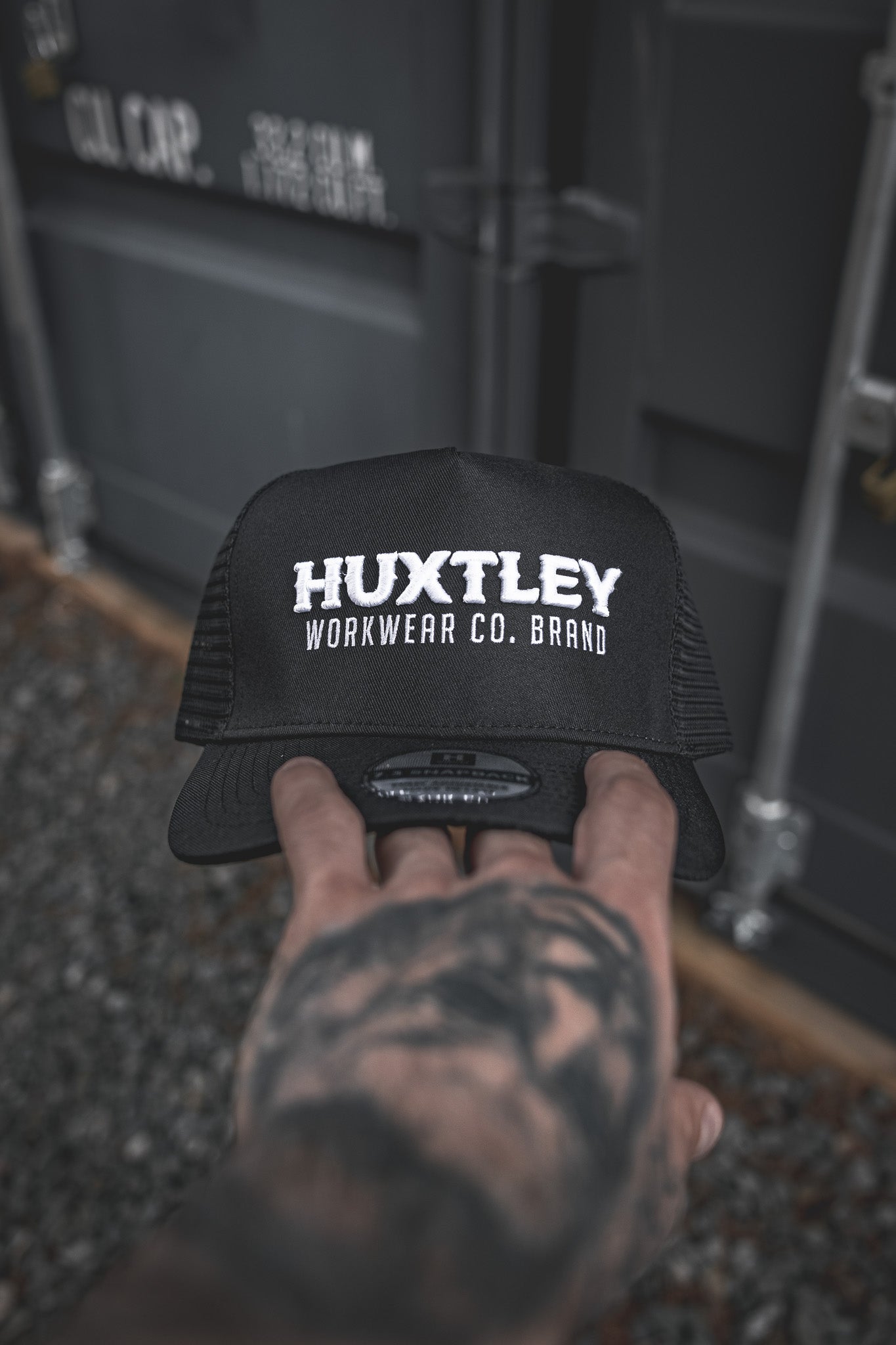
                  
                    Close-up of the Huxtley Workwear Co. Brand trucker cap front logo. Embroidered in bold white on black, this cap means business—on site and off.
                  
                