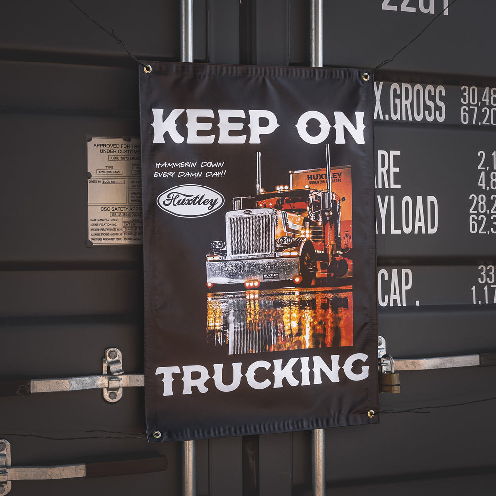 Fly the flag of hard work with our Huxtley “Keep On Trucking” banner. Featuring a big rig lit up like a beast and the motto that fuels jobsite legends: Hammerin’ Down Every Damn Day!